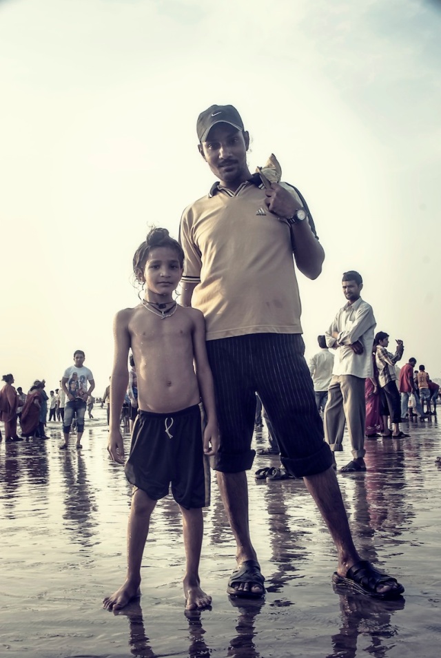 On a day off, a Sikh father takes his son for a swim on the beach whilst celebrating the Ganpati festival on Juhu beach in Mumbai